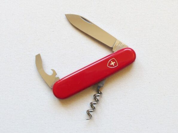 a red pocket knife with a corkscrew